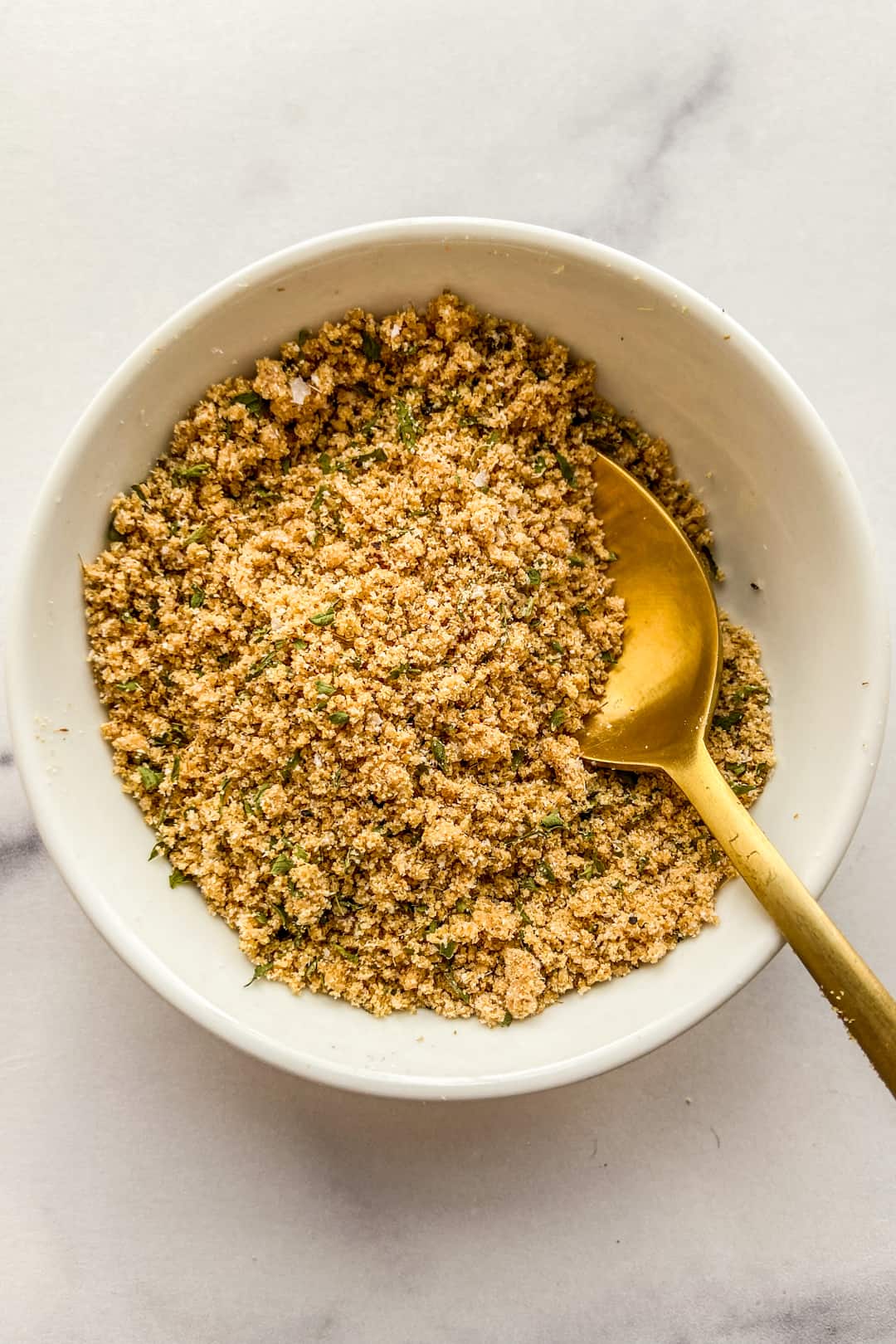 A ramen seasoning spice blend in a small white bowl with a gold spoon.