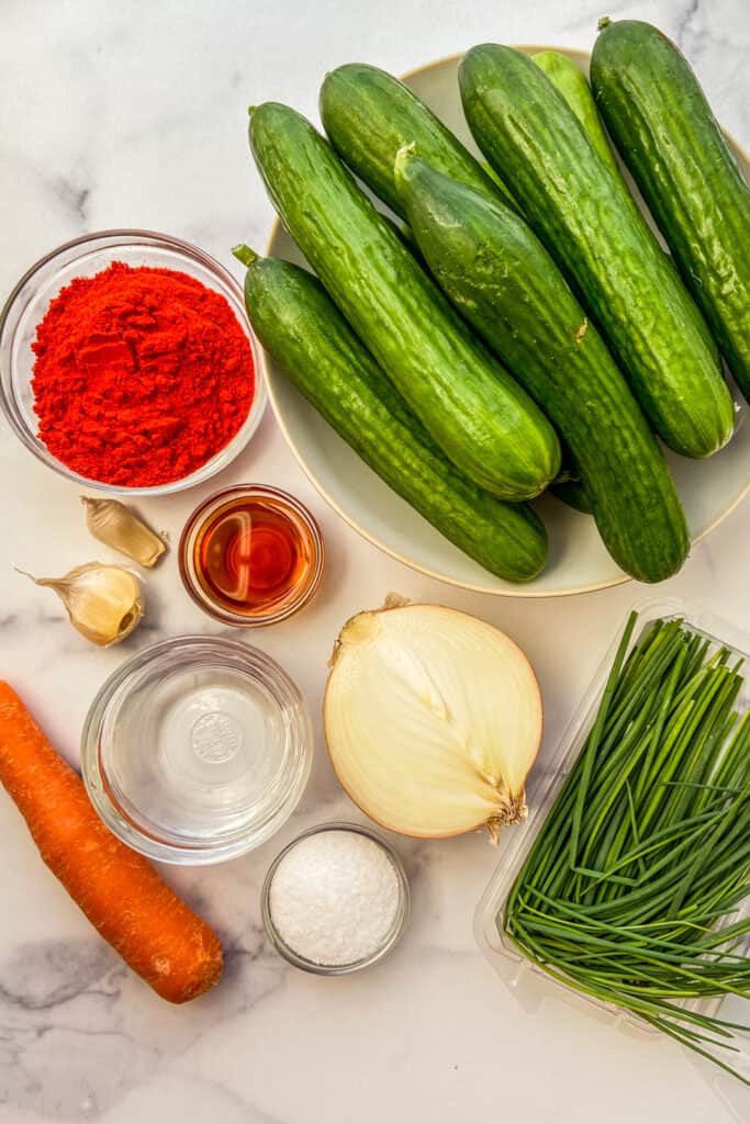 Ingredients for kimchi cucumbers on a marble background.