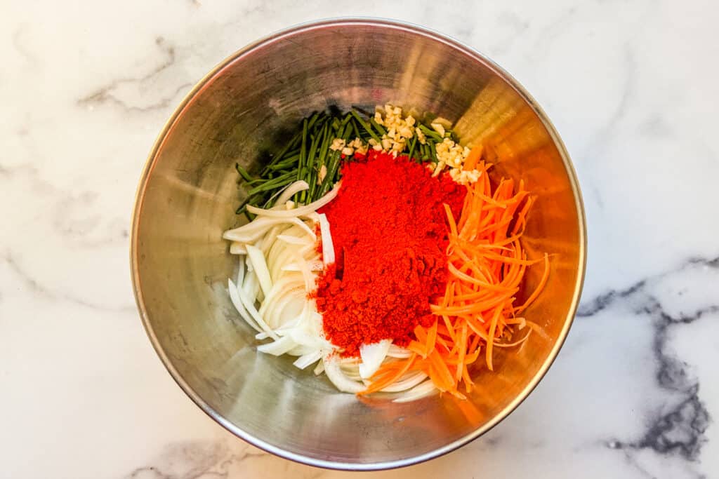 Kimchi stuffing ingredients, including shredded carrots, chives, onions, and Gochugaru.