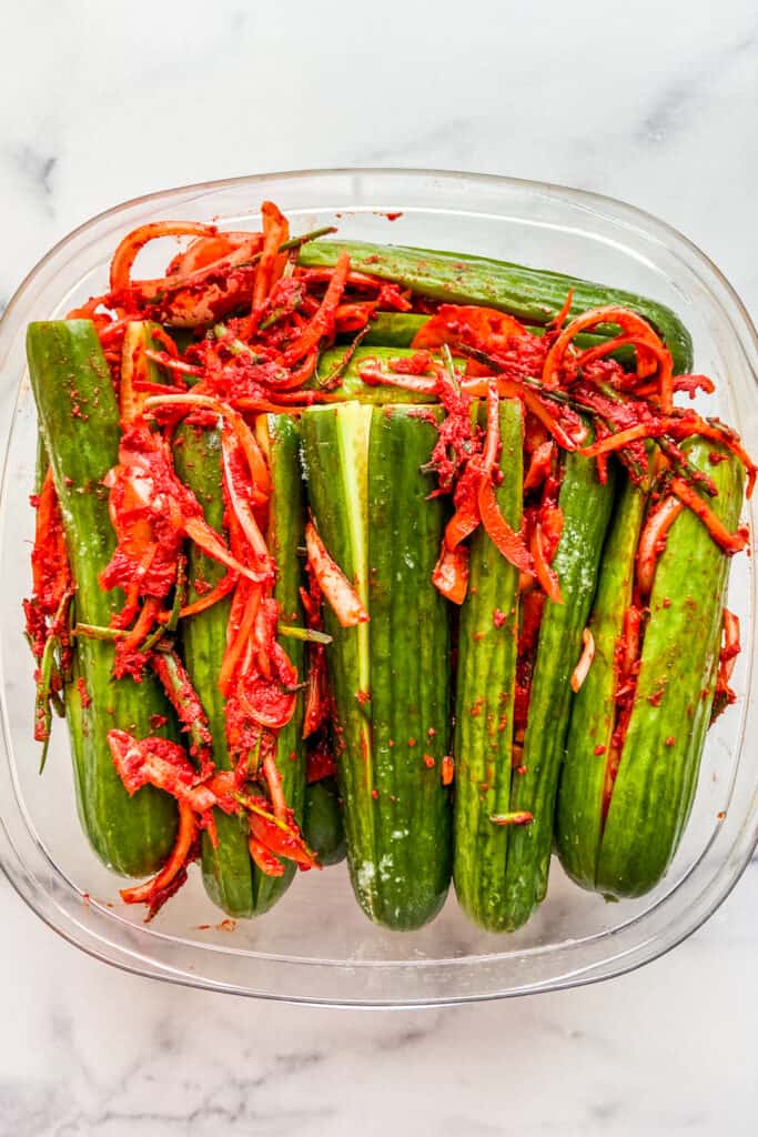 Kimchi cucumbers in a plastic container before going into the refrigerator.