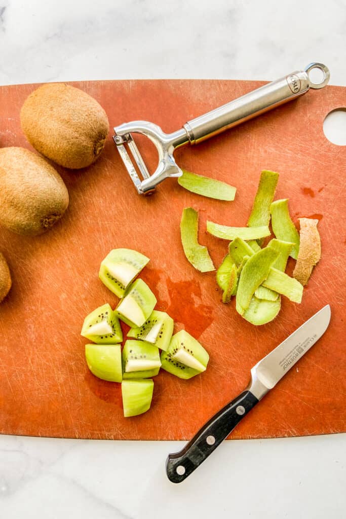 Peeling kiwi on a cutting board.