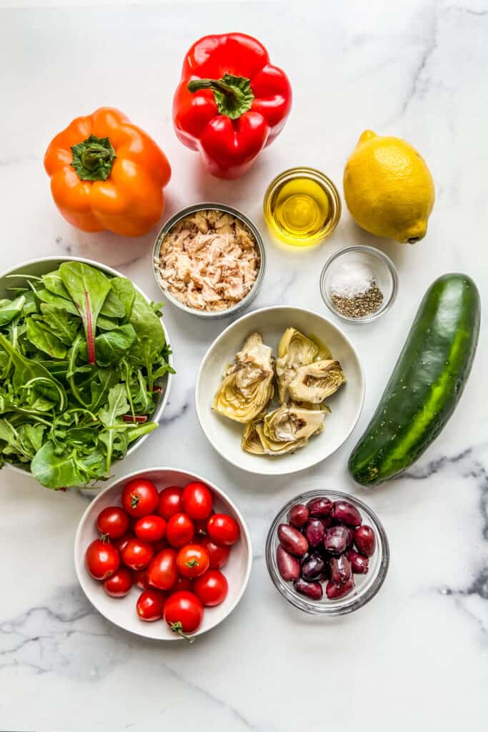 Ingredients for a tuna Mediterranean salad on a marble background.