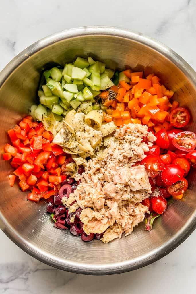 Chopped vegetables, tuna, and greens in a large mixing bowl.