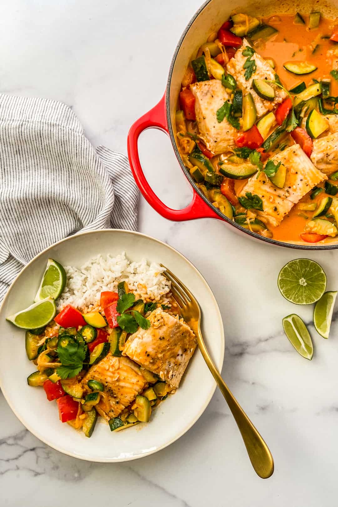 Thai fish curry with rice in a bowl, next to a pot of curry.