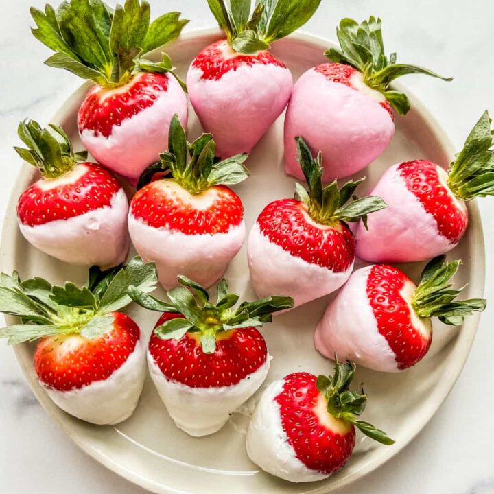 Yogurt covered strawberries on a white plate.