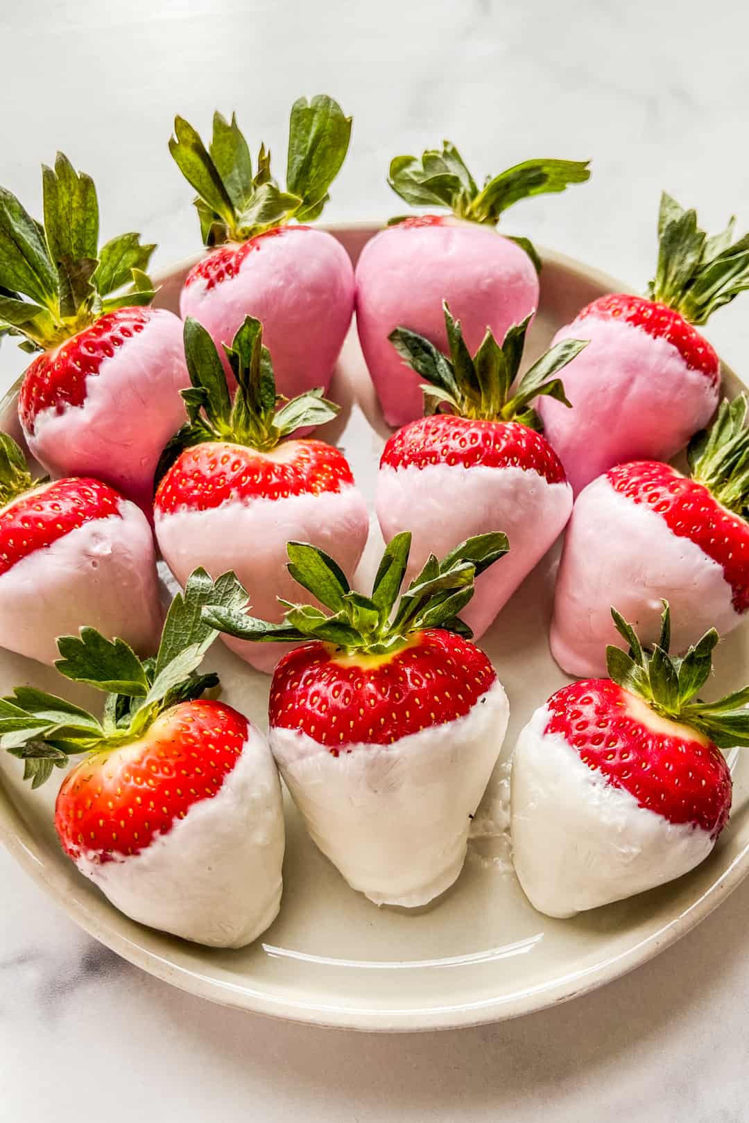 A closeup of yogurt covered strawberries on a small, white plate.