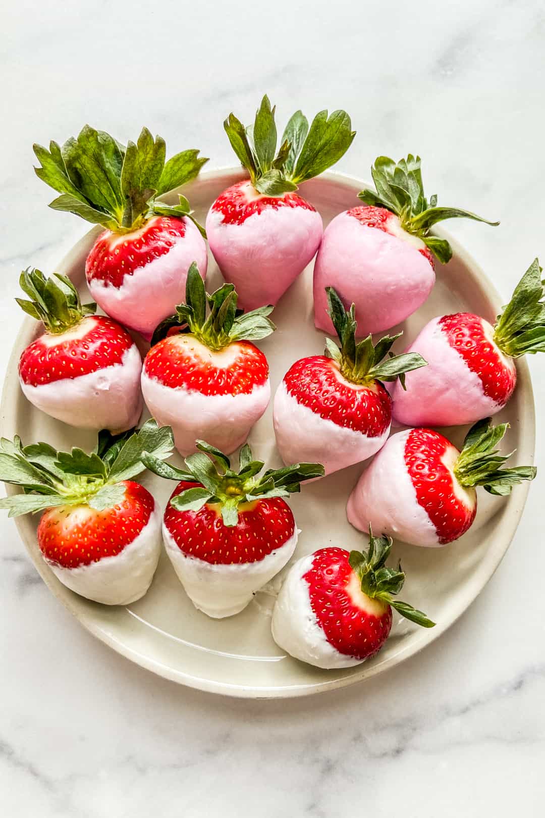 Yogurt covered strawberries on a white plate.