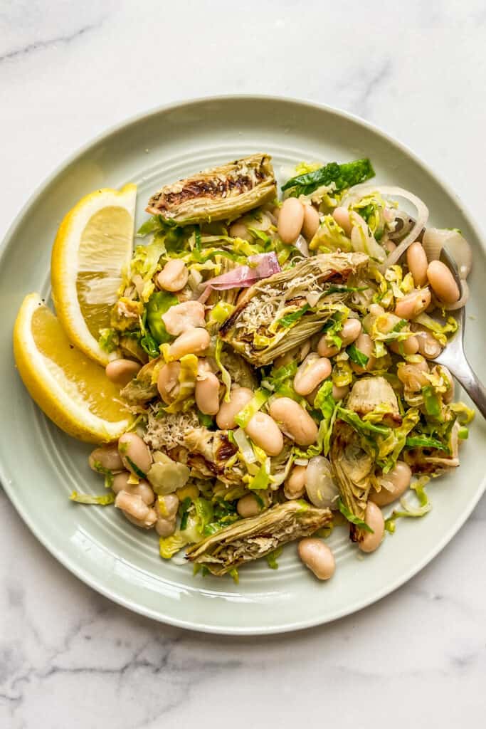 A Brussels sprouts, white bean, and roasted artichoke salad on a plate.