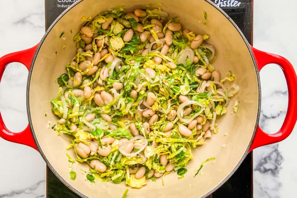 Brussels sprouts and white beans in a dutch oven.