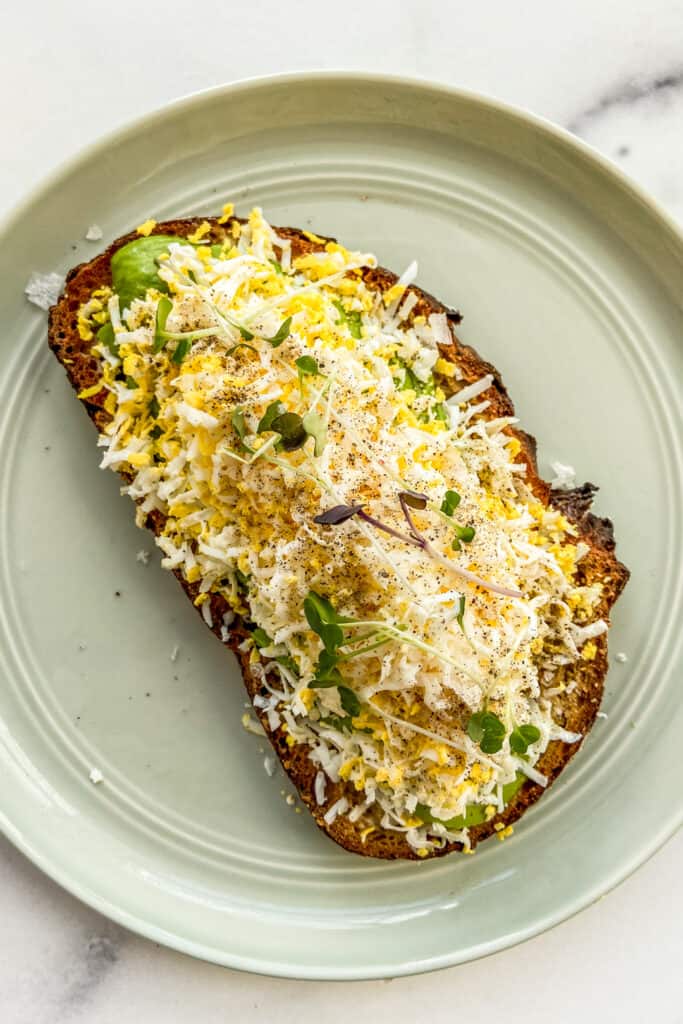 Grated egg avocado toast on a small green plate.