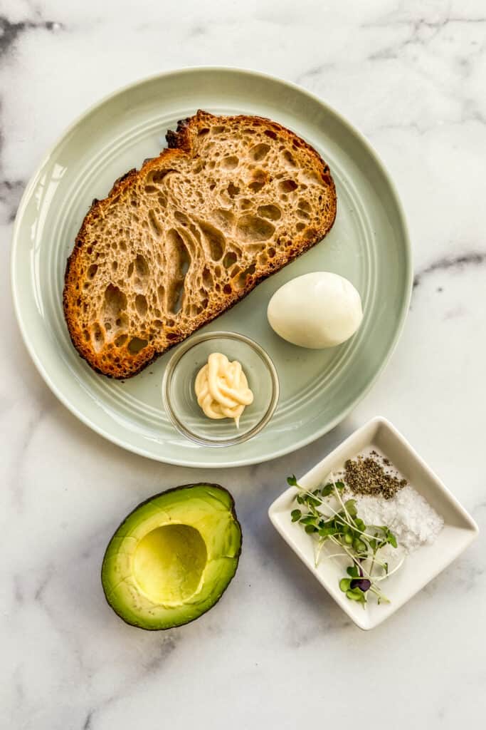 Toast, a hardboiled egg, mayo, avocado, salt, pepper, and microgreens.