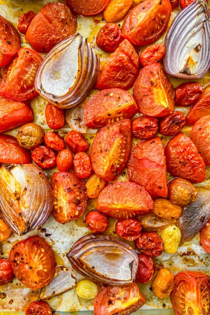 A closeup shot of roasted tomatoes and onion after coming out of the oven.