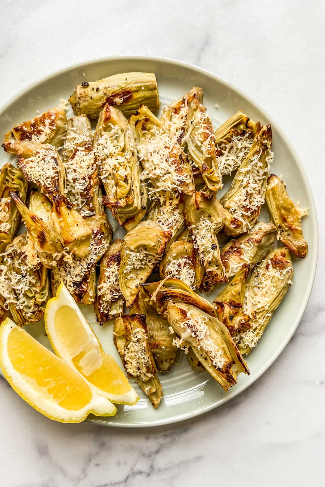 Roasted artichoke hearts with lemon slices on a plate.