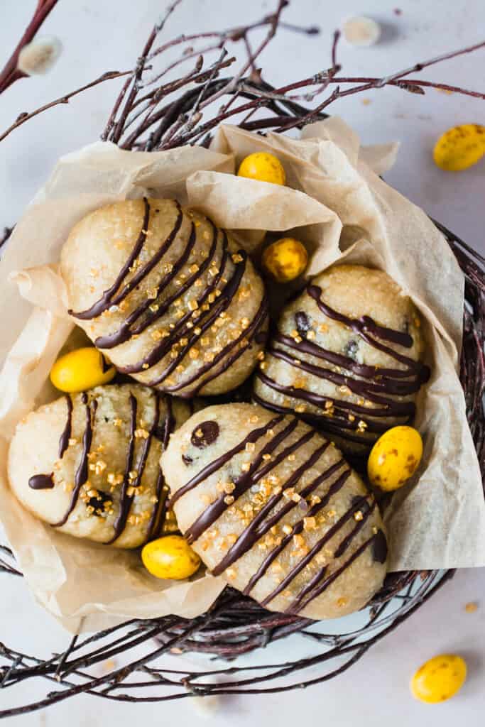 Cookie dough eggs with a chocolate drizzle in a basket.