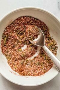 Cajun seasoning blend in a small white bowl with a spoon.