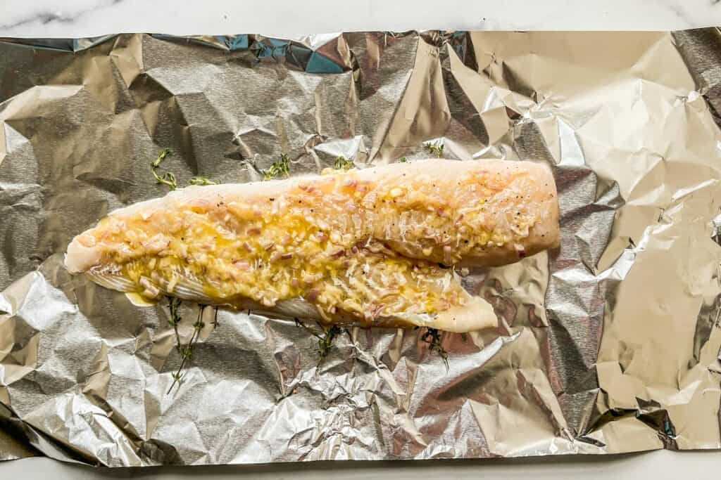 Butter covered cod on a piece of foil.