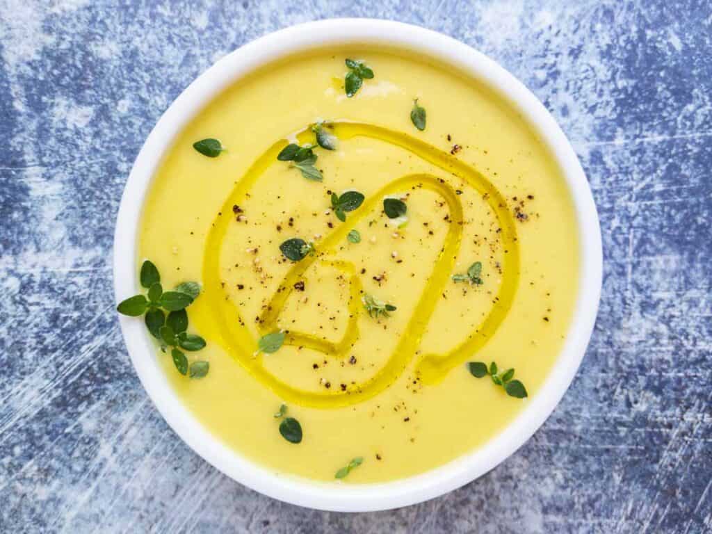 Creamy summer squash soup on a blue background.