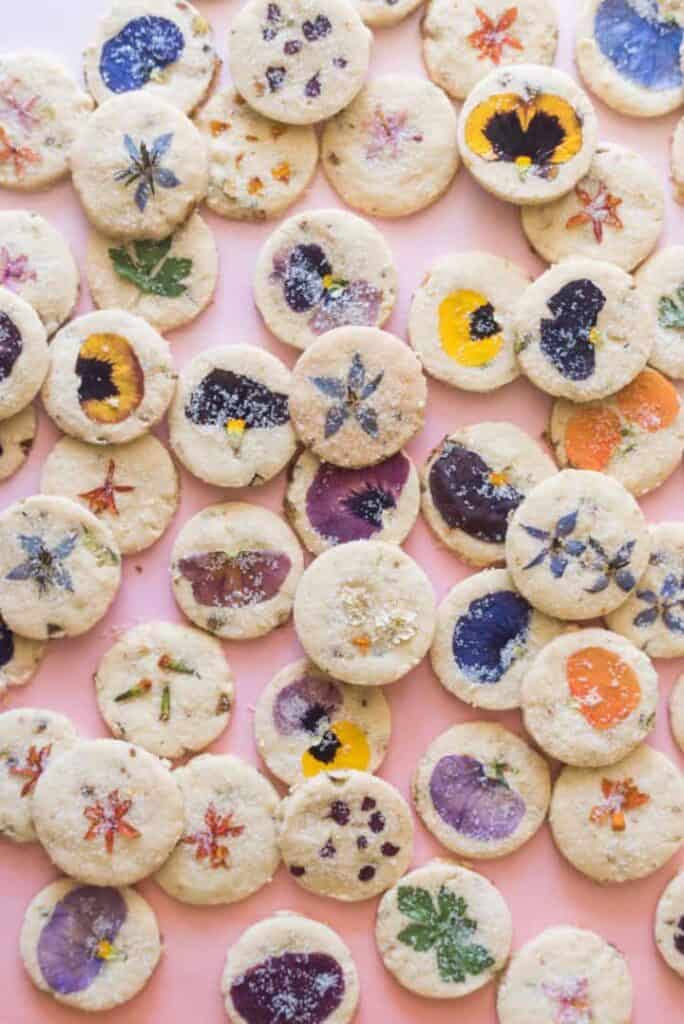 Edible flower shortbread cookies on a pink background.