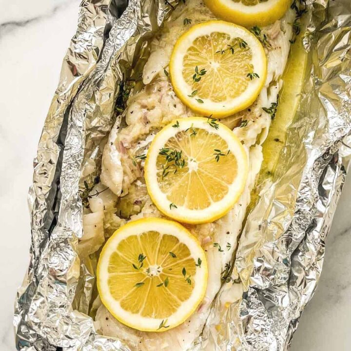 Grilled cod in foil topped with lemon slices.