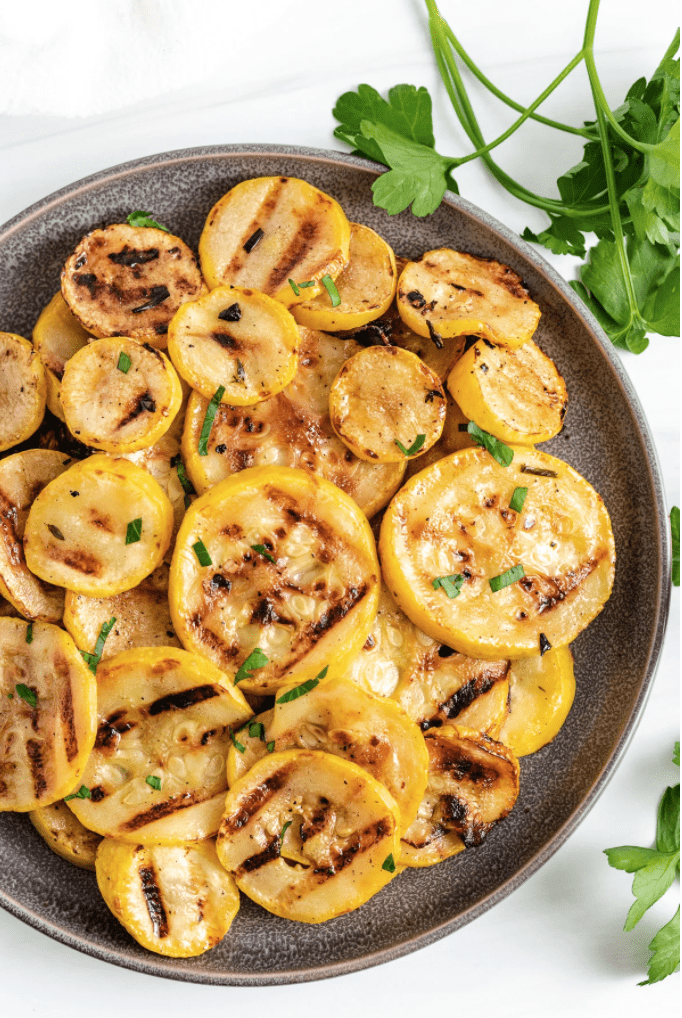 Grilled yellow squash on a grey plate.