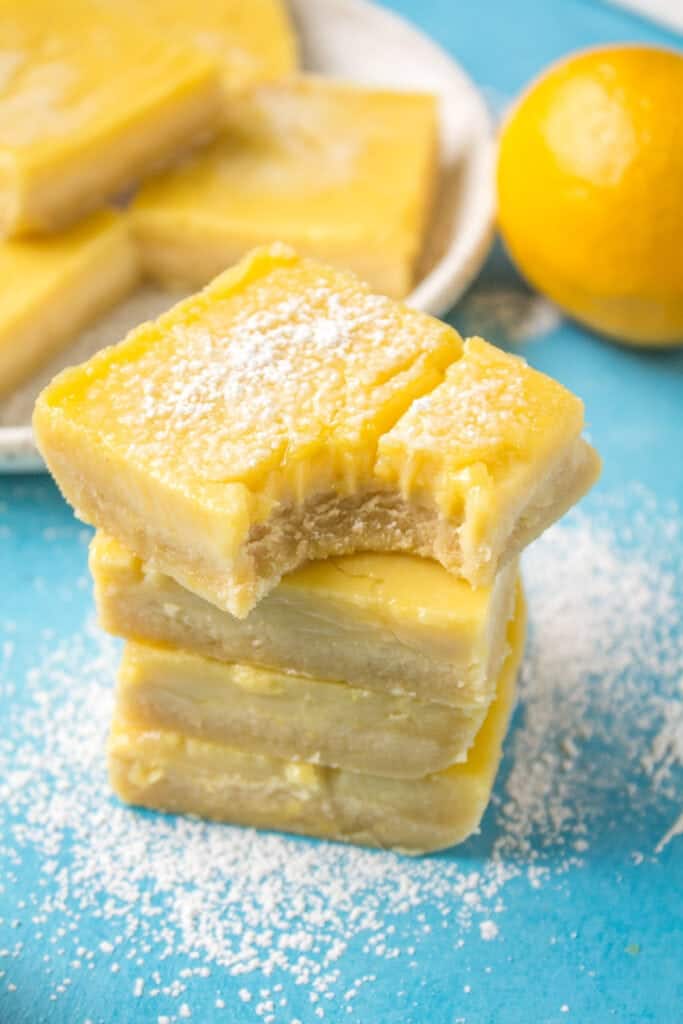 Healthy lemon bars in a stack on a blue background.