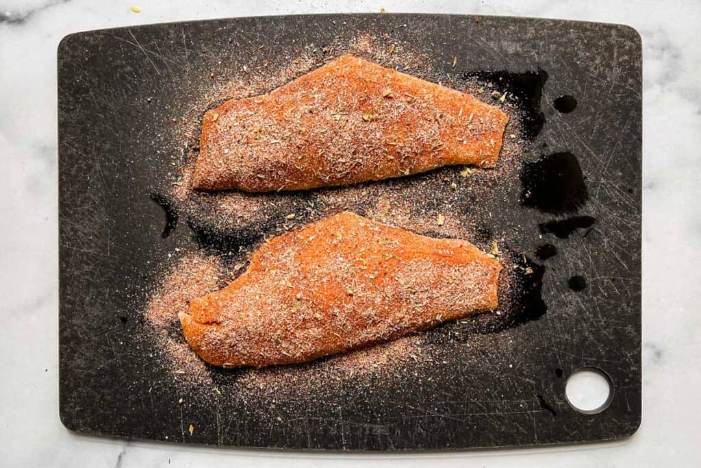 Spice rubbed snapper on a cutting board.