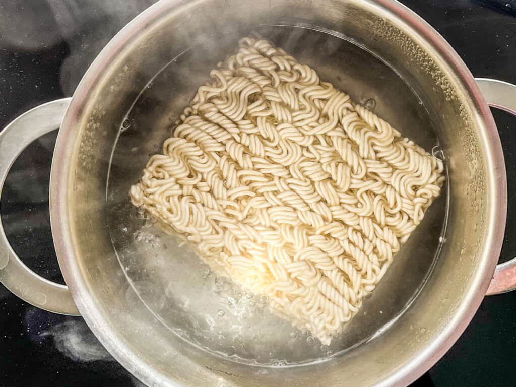 Ramen noodles cooking in a small pot.
