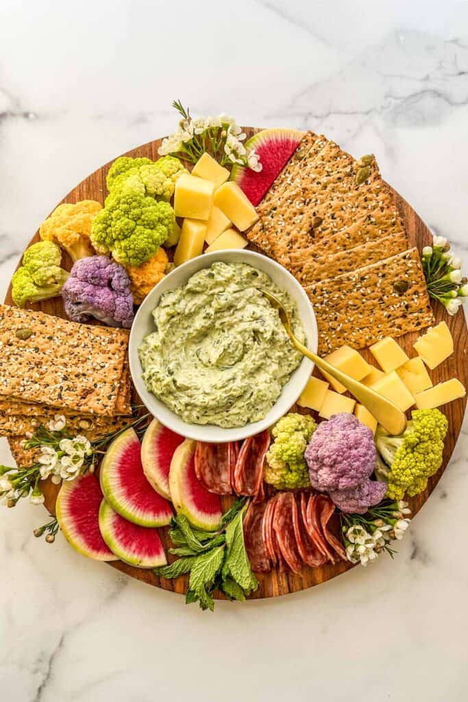 A round wooden plate with spring snacking items.