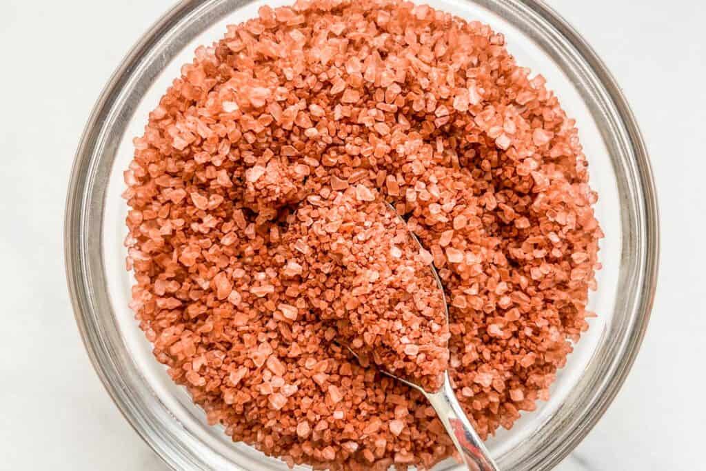 Red Hawaiian salt in a glass bowl with a small spoon.