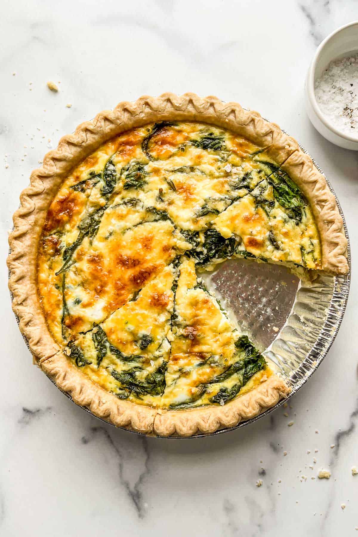 A duck egg quiche with a slice cut out of it.