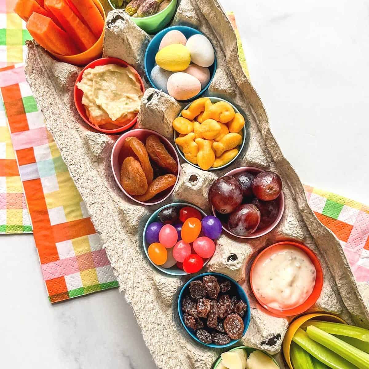 An Easter snack box for kids made from an egg carton, plastic eggs, and little snacks.