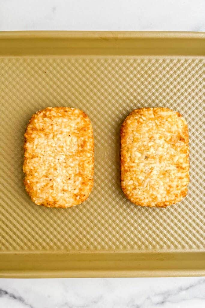 Two hash browns on a gold baking sheet.