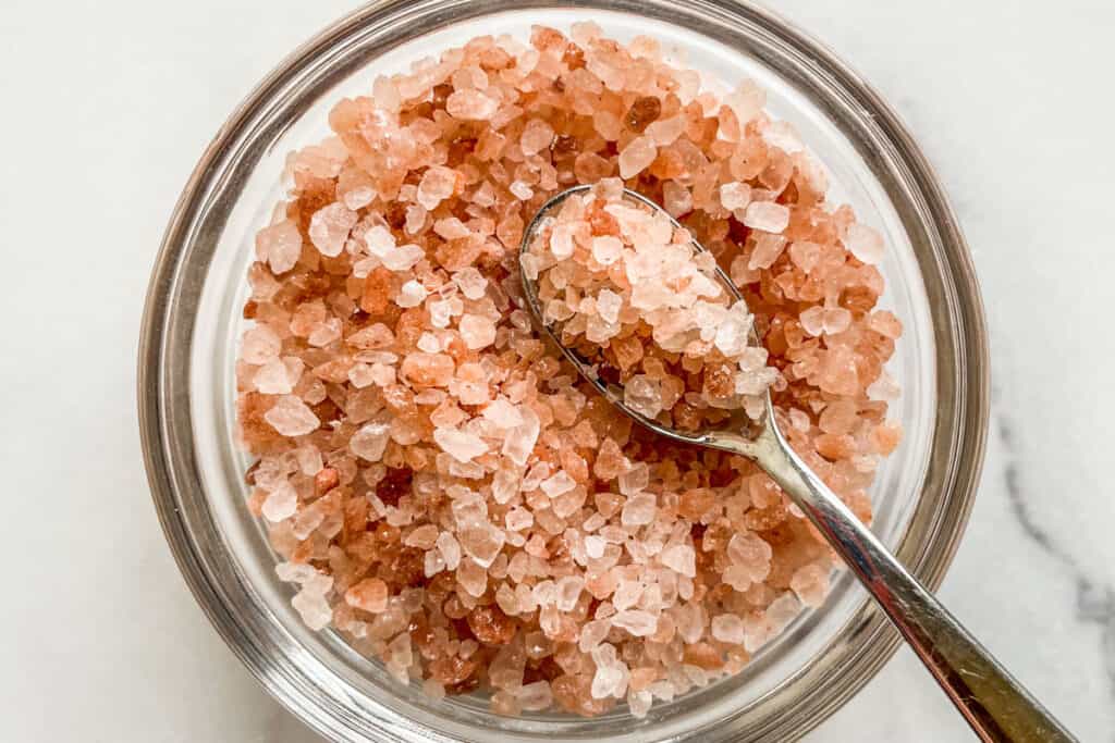 Himalayan pink salt in a glass bowl with a spoon.