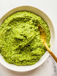 Ramp pesto in a white bowl with a gold spoon.
