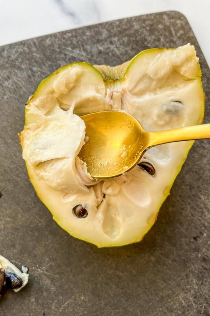 A spoon scooping out a piece of cherimoya.