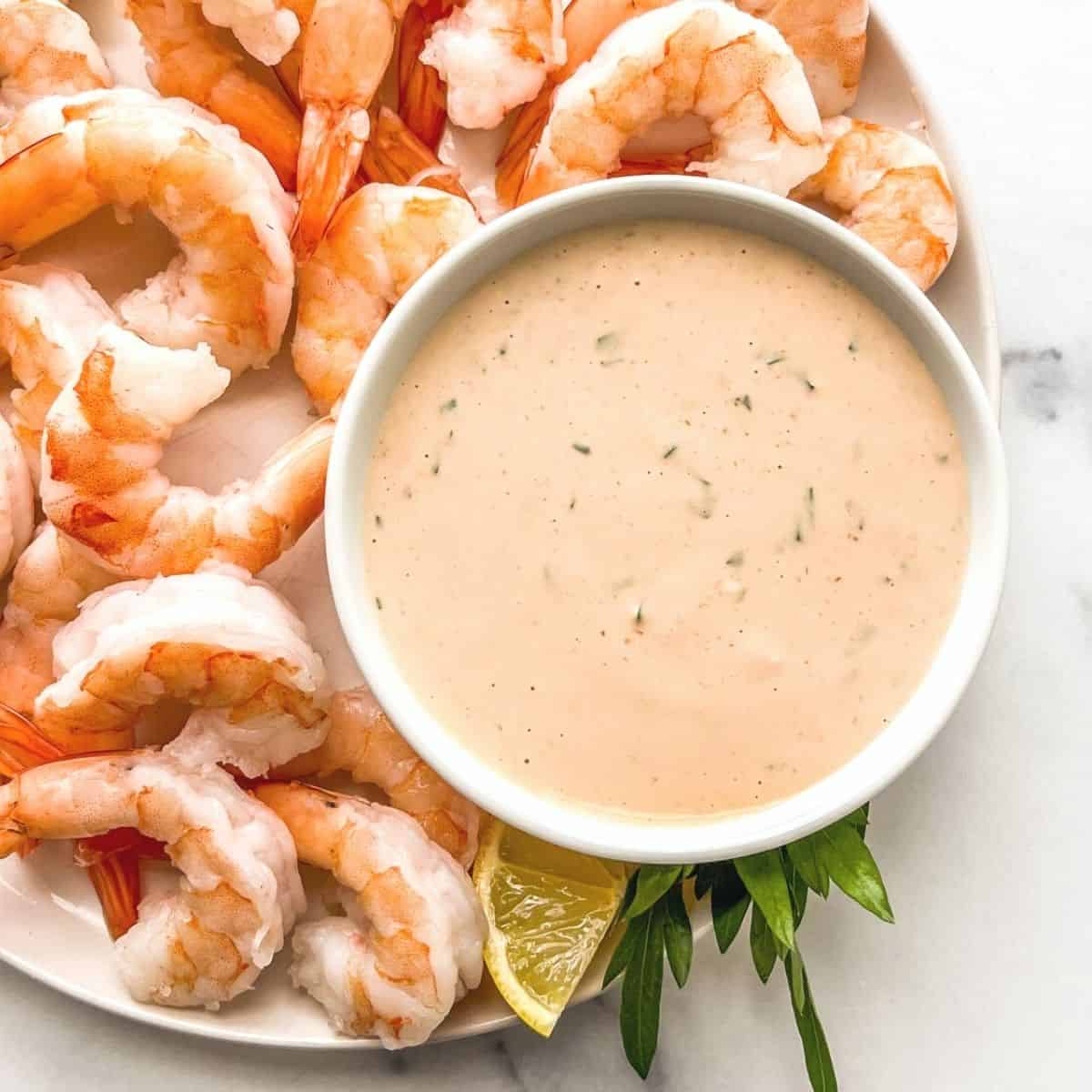 A seafood sauce in a bowl next to shrimp.