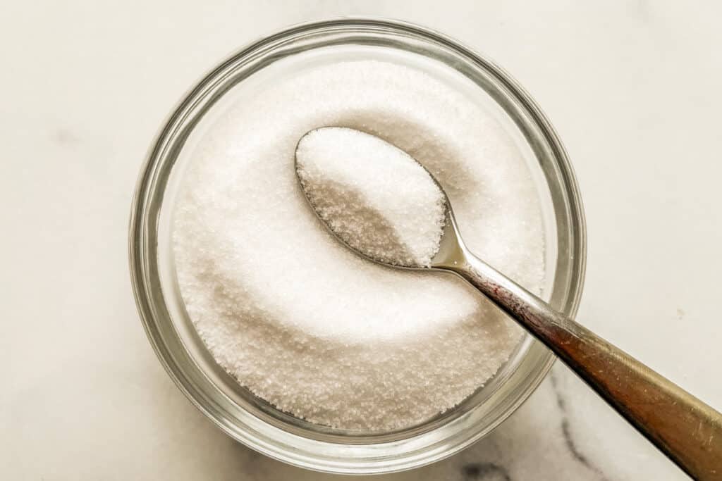 Table salt in a small glass bowl with a spoon.