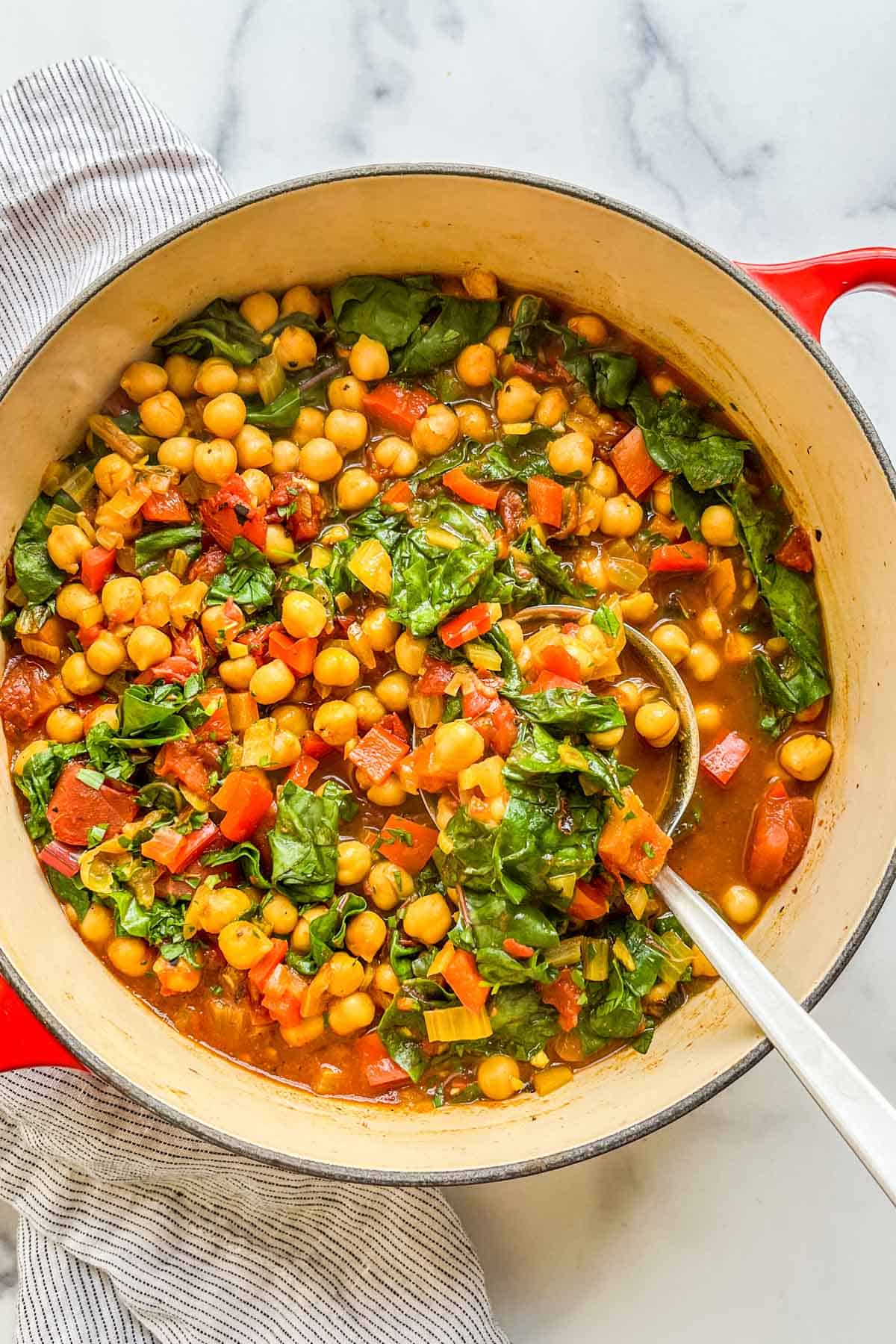 Chickpea stew in a large dutch oven with a ladle.