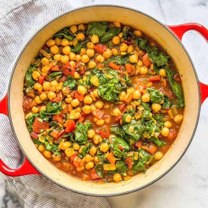 Chickpea chard stew with tomatoes in a red dutch oven.