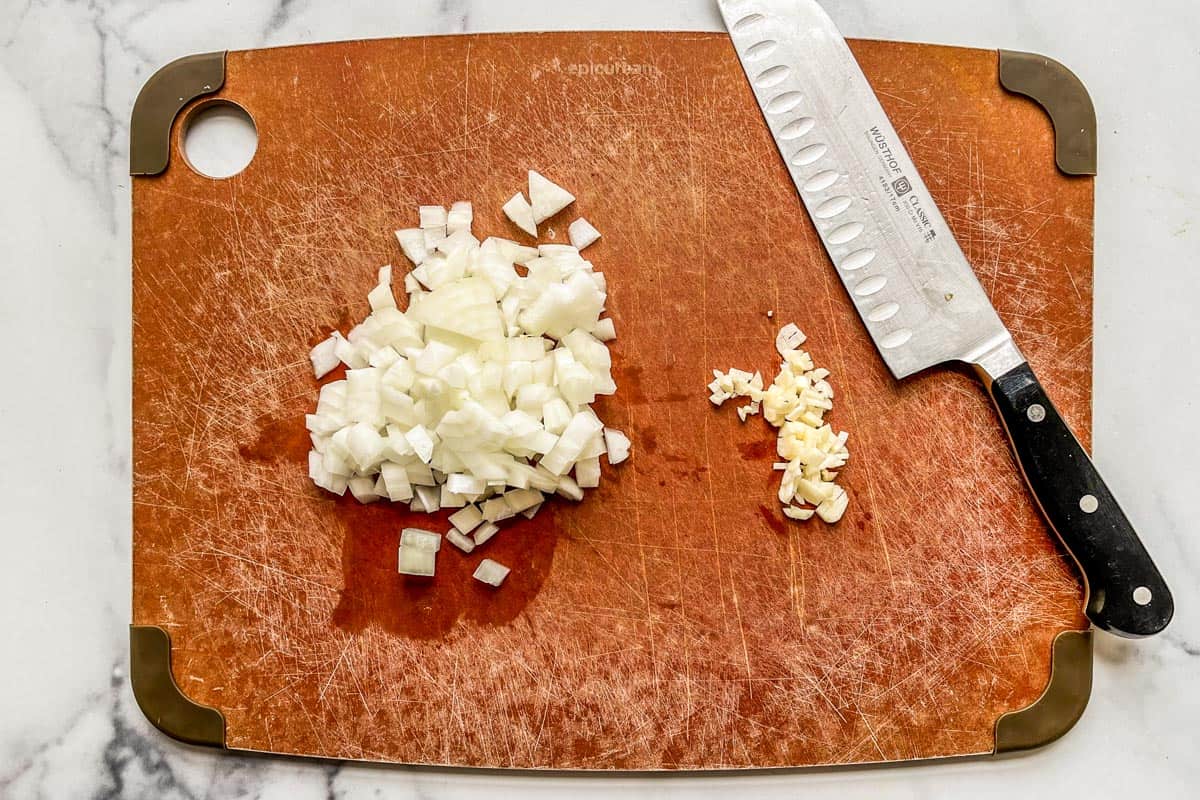 Diced onions and garlic on a cutting board.