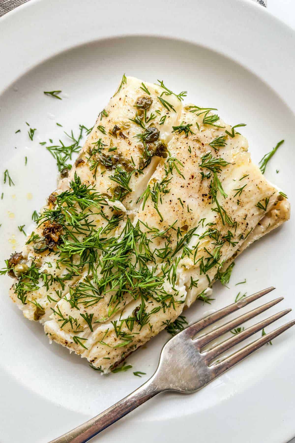 An easy pan seared halibut fillet on a white plate.