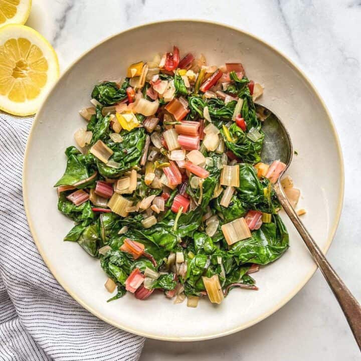 Sauteed swiss chard in a serving bowl with a spoon.