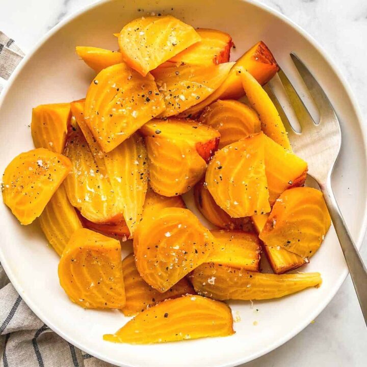 Roasted golden beets in a serving dish with a fork.