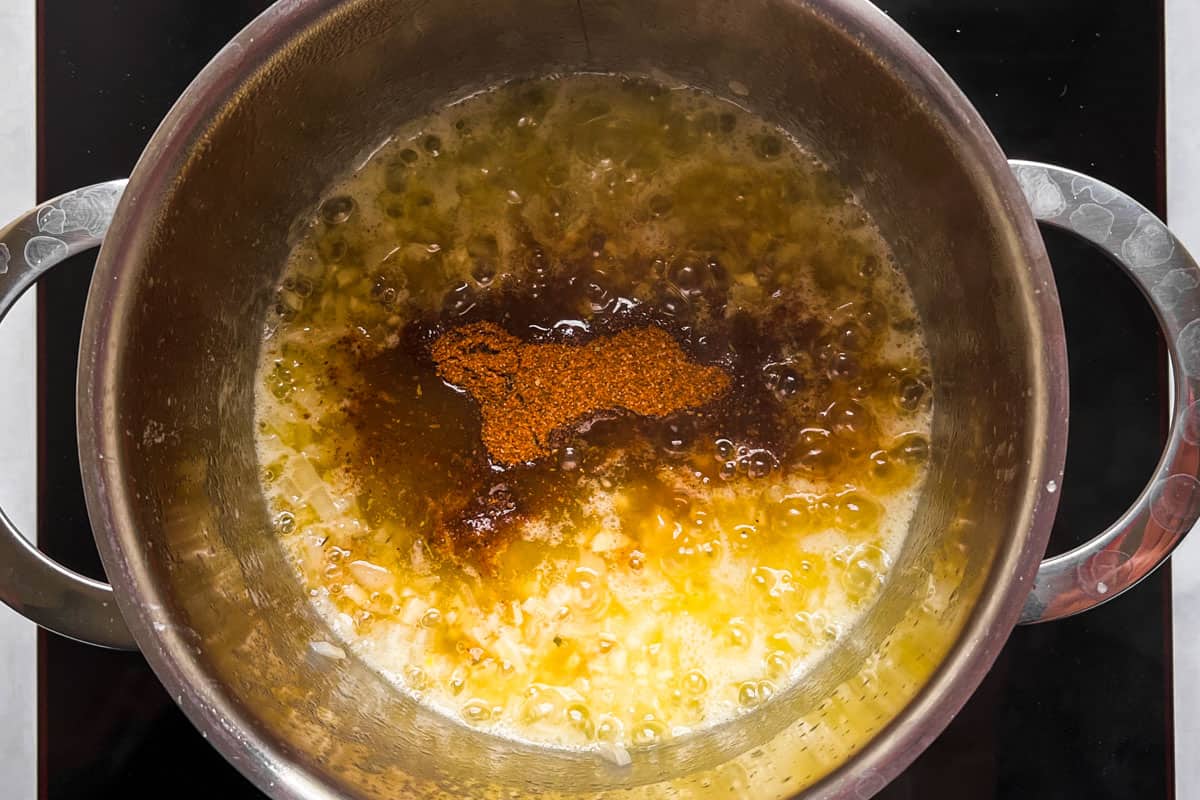 A pot of butter with spices cooking on a stovetop.