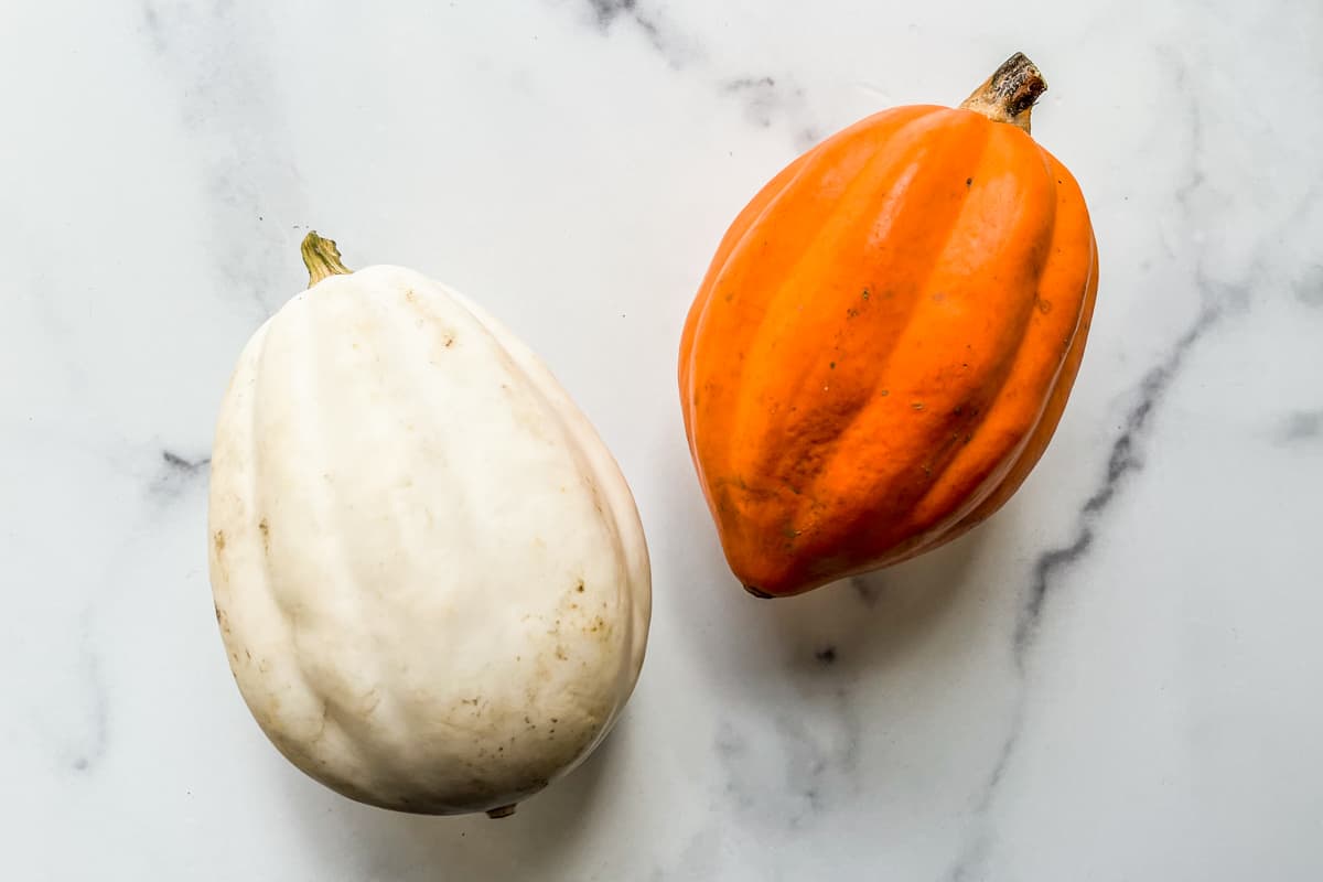 A white and an orange acorn squash.