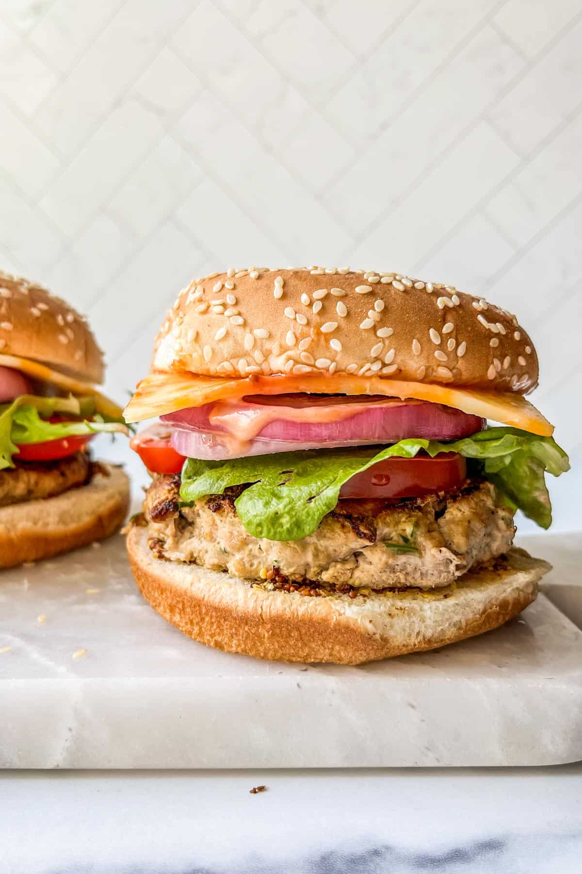 A healthy, grilled turkey burger with vegetables and cheese on a bun.