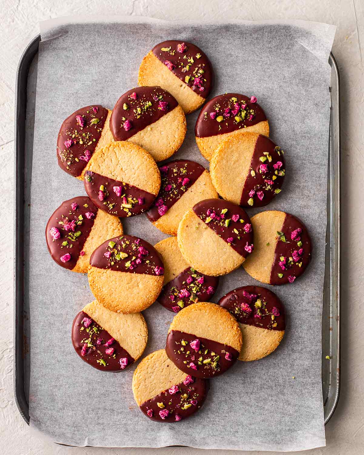 Almond flour shortbread cookies dipped in chocolate on a baking sheet.