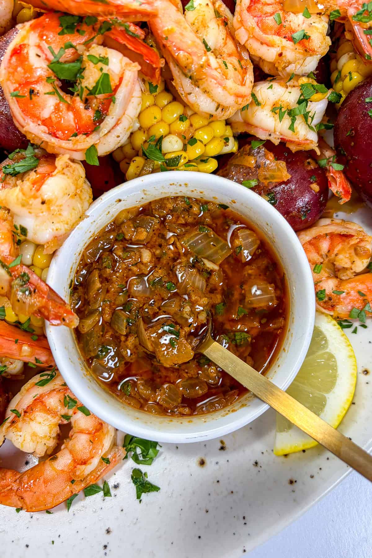 Cajun butter seafood boil sauce in a white bowl with a gold spoon.