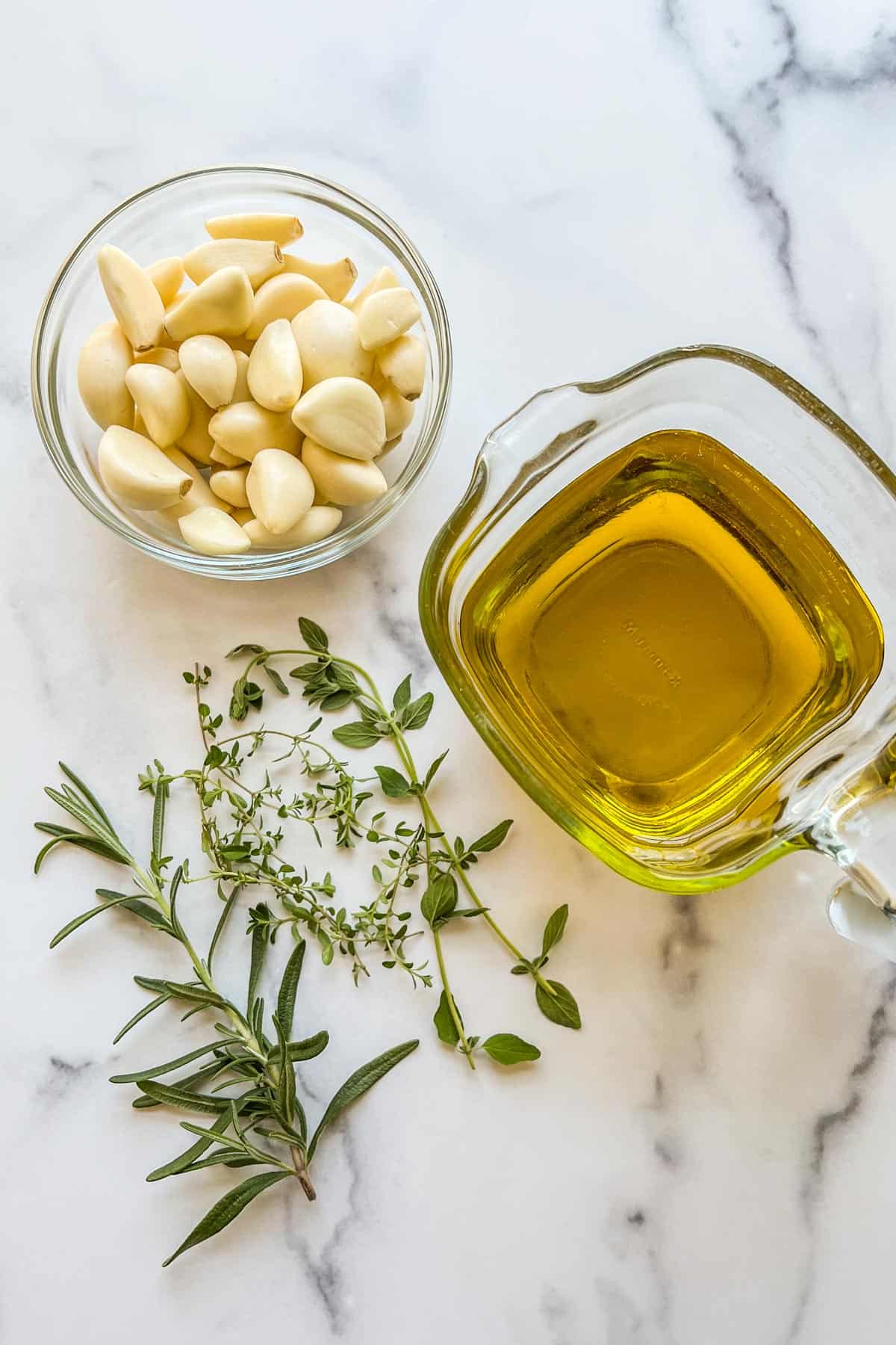 Garlic cloves, oil, and fresh herbs.