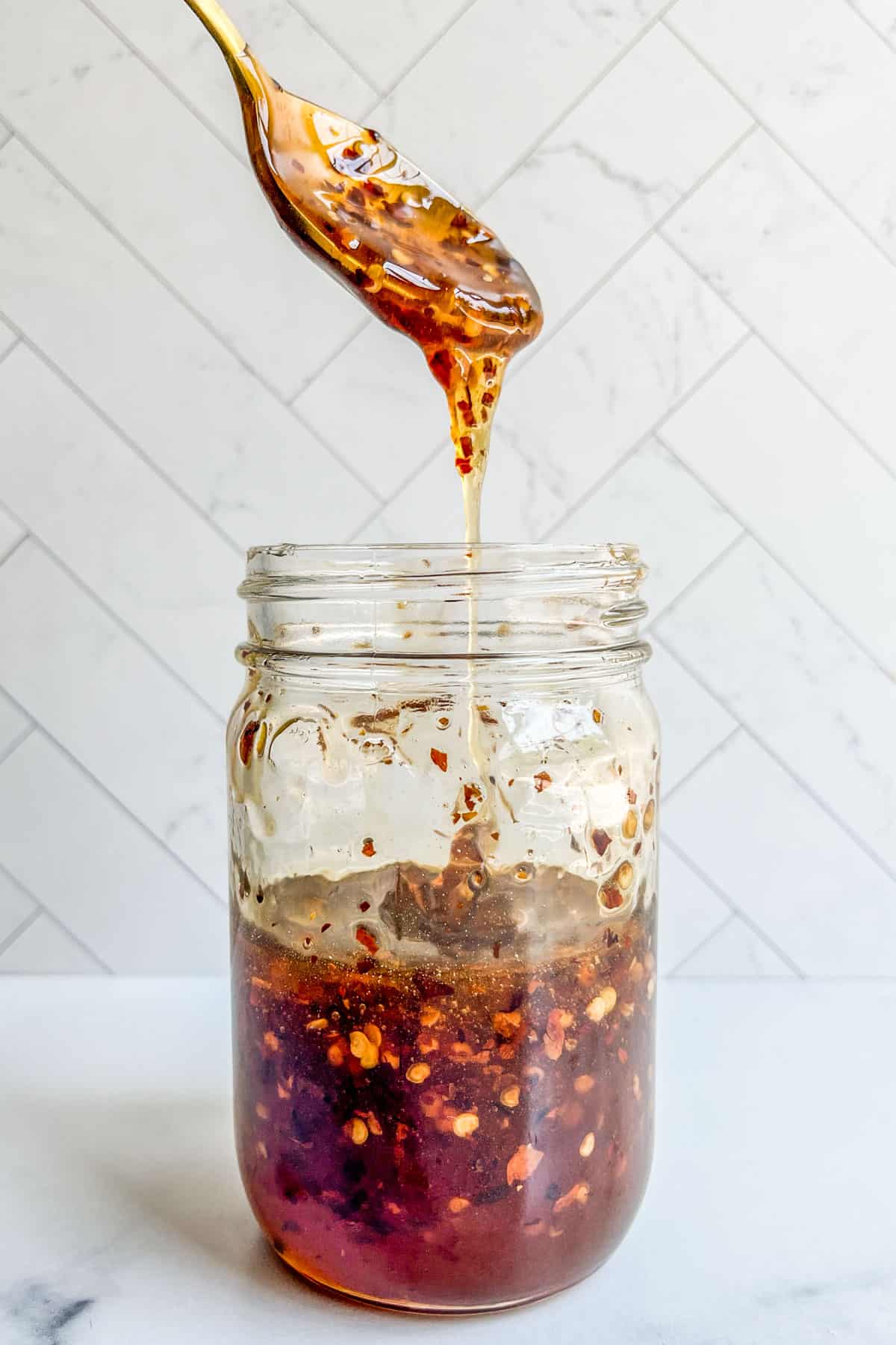Hot honey in a jar with a spoon above it.